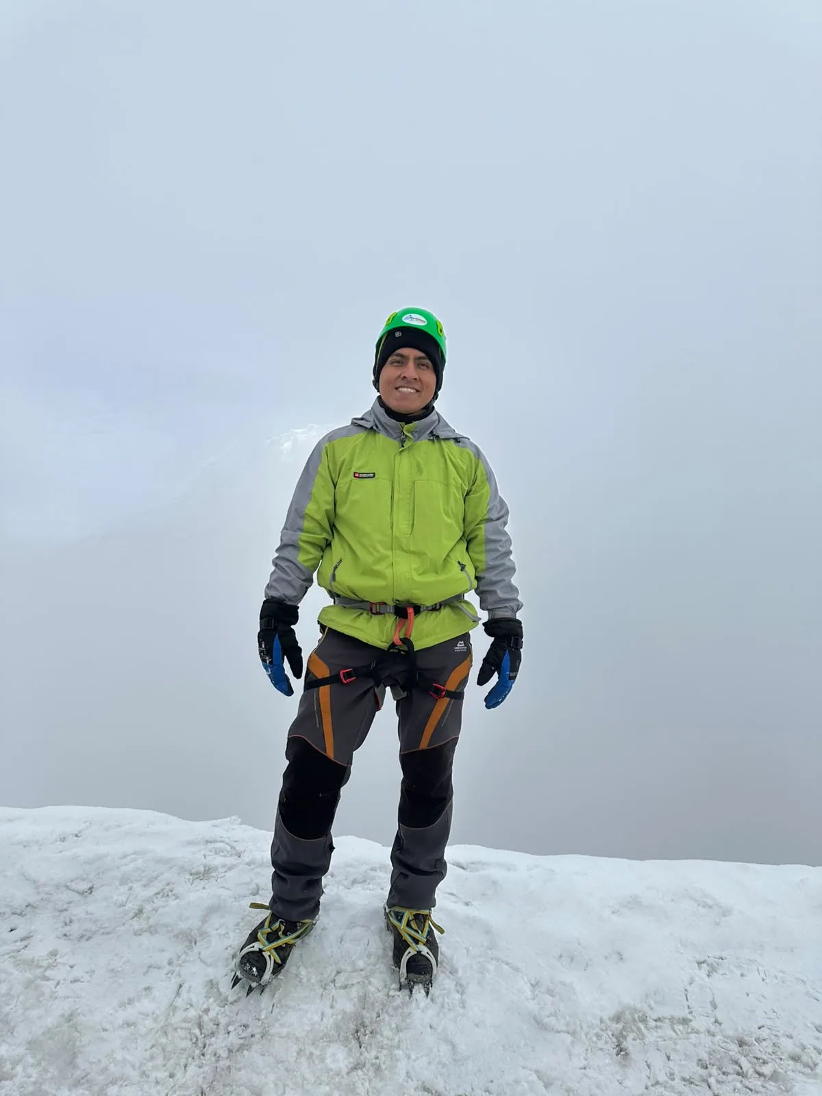Jhoel Velasco en la cumbre de una montaña nevada con equipo de alpinismo